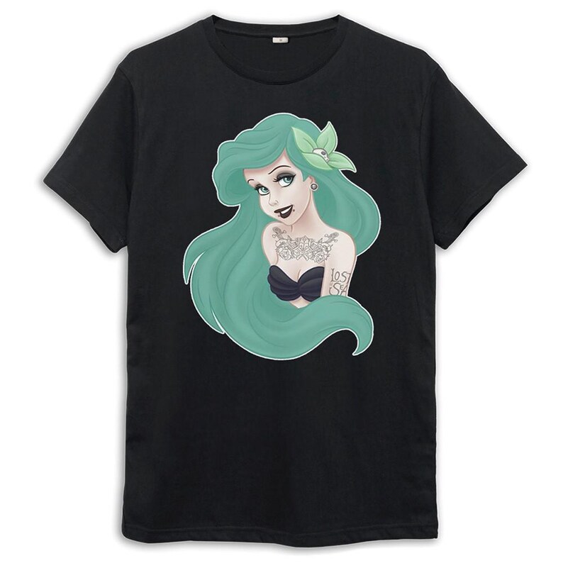 Puede incluir: Camiseta negra con una ilustraci&oacute;n de una sirena de pelo verde. La sirena tiene tatuajes y una flor en el pelo. El texto "Lost at Sea" es visible en su brazo.