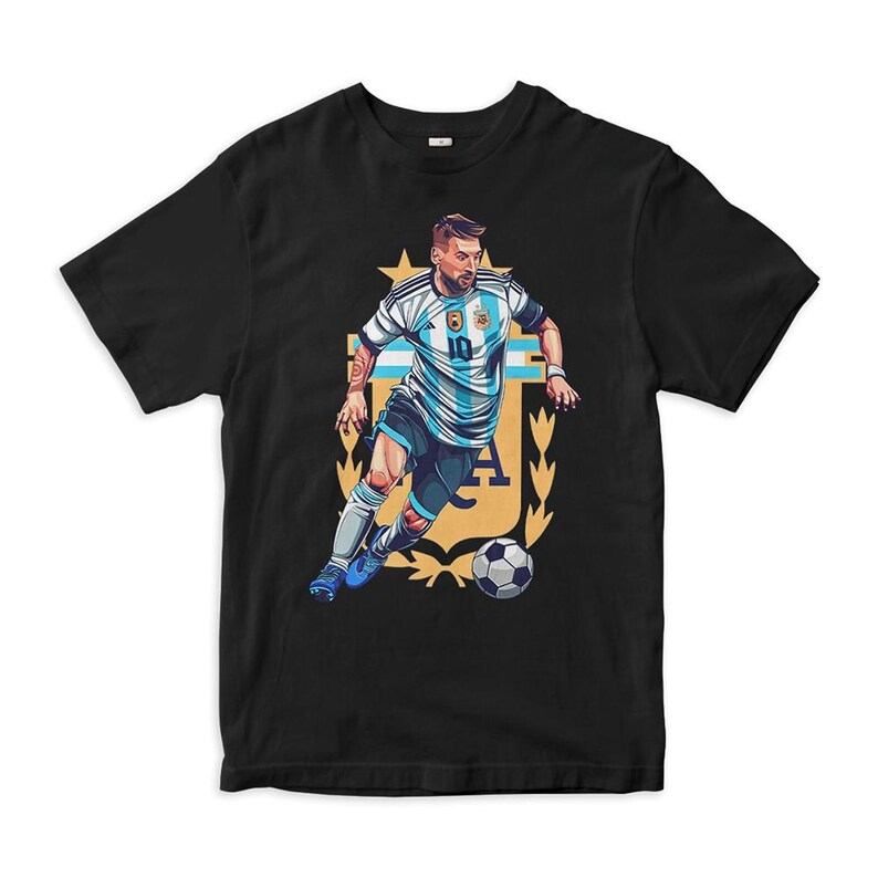 May include: Black t-shirt with a graphic of a soccer player wearing a light blue and white jersey with the number 10 on it. The player is dribbling a soccer ball and is surrounded by a gold crest with the letters "AFA".