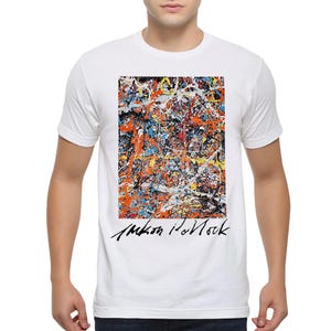May include: White t-shirt with a colorful abstract painting on the front. The painting is in shades of blue, yellow, orange, and red. The artist's signature, "Jackson Pollock", is printed below the painting.