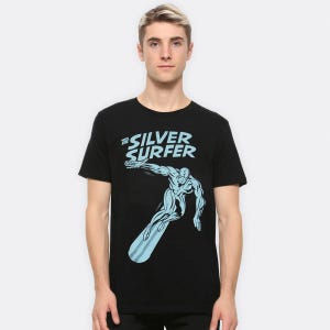 May include: Black t-shirt with a light blue graphic of the Silver Surfer surfing. The text "THE SILVER SURFER" is above the graphic in light blue. The t-shirt is a crew neck style.