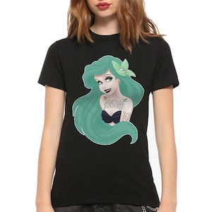 Puede incluir: Camiseta negra con un gr&aacute;fico de una sirena de pelo verde con tatuajes y el texto "Lost at Sea".