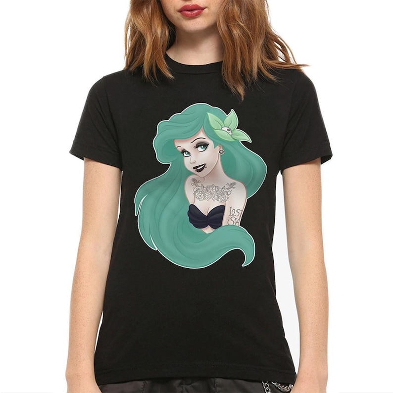 Puede incluir: Camiseta negra con un gr&aacute;fico de una sirena de pelo verde con tatuajes y el texto "Lost at Sea".