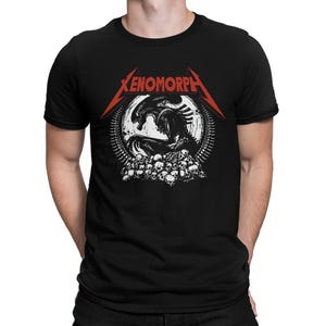 May include: Black t-shirt with a white and black Xenomorph graphic, a skull pile, and the word "Xenomorph" in red. The shirt has a crew neck and short sleeves.