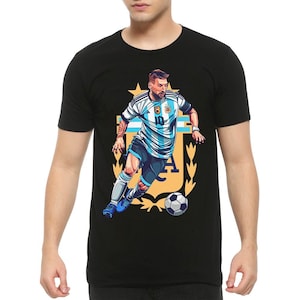 May include: Black t-shirt with a graphic of a soccer player in a blue and white jersey with the number 10 on the front. The player is dribbling a soccer ball and is surrounded by a gold crest with the letters "A" and "F" visible.