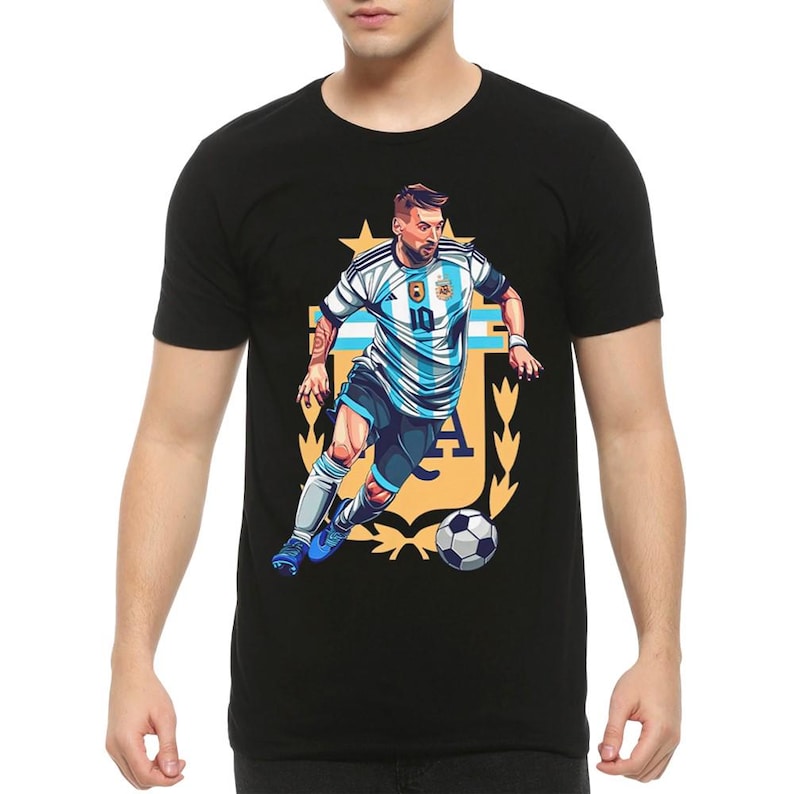 May include: Black t-shirt with a graphic of a soccer player in a blue and white jersey with the number 10 on the front. The player is dribbling a soccer ball and is surrounded by a gold crest with the letters "A" and "F" visible.