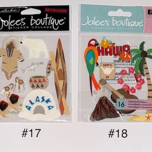 May include: Two sticker packs with a destination theme. The first pack features a brown and white sticker of a person wearing a brown and white outfit, a white polar bear, a brown and white canoe, a white and blue sticker with the word "Alaska" on it, and other stickers. The second pack features a red, green, and blue sticker of a parrot, a brown and white sticker of a palm tree, a brown and white sticker of a volcano, and other stickers. The text "Jolee's Boutique" is on both packs.