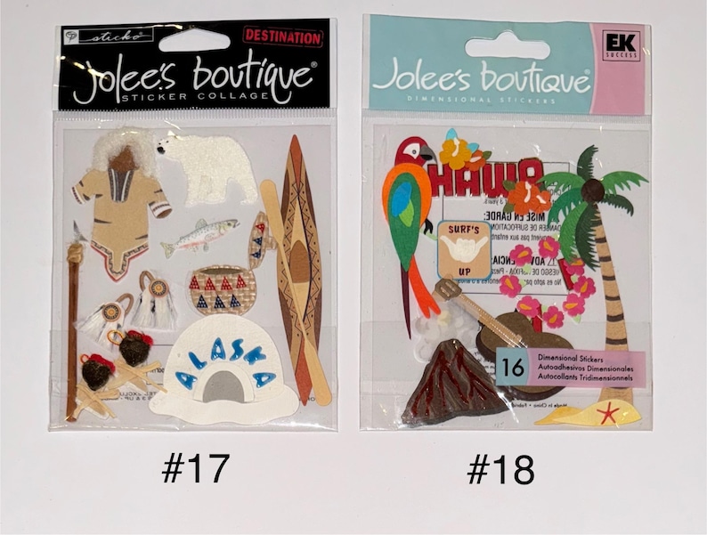 May include: Two sticker packs with a destination theme. The first pack features a brown and white sticker of a person wearing a brown and white outfit, a white polar bear, a brown and white canoe, a white and blue sticker with the word "Alaska" on it, and other stickers. The second pack features a red, green, and blue sticker of a parrot, a brown and white sticker of a palm tree, a brown and white sticker of a volcano, and other stickers. The text "Jolee's Boutique" is on both packs.