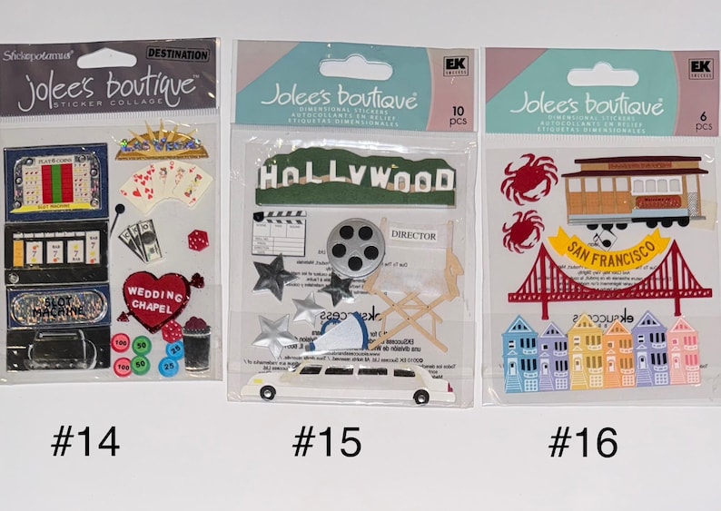 May include: Three packs of dimensional stickers featuring various themes. The first pack has a Las Vegas theme with images of a slot machine, wedding chapel, dice, and playing cards. The second pack has a Hollywood theme with images of a film reel, director's chair, and a limousine. The third pack has a San Francisco theme with images of a cable car, the Golden Gate Bridge, and houses.