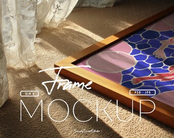 May include: A wooden picture frame mockup with a colorful abstract design. The frame is rectangular and has a light brown finish. The artwork features pink, blue, and red shapes. The text "Frame MOCKUP" is visible in the image.