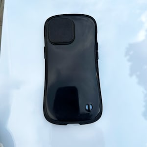 K&ouml;nnte beinhalten: Eine schwarze Handyh&uuml;lle mit einem erh&ouml;hten Kameraobjektivabdeckung.