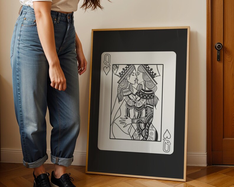 Puede incluir: Impresi&oacute;n art&iacute;stica enmarcada en blanco y negro que presenta una ilustraci&oacute;n estilizada de dos reinas bes&aacute;ndose, al estilo de una carta de juego. La obra de arte est&aacute; sobre un fondo negro con un marco dorado. La carta est&aacute; etiquetada con un coraz&oacute;n y una pica.