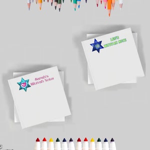 May include: Two white notepads with colorful star designs and personalized text. The top notepad says "Leo's Mitzvah Note" and the bottom notepad says "Sarah's Mitzvah Notes". Both notepads are surrounded by colored pencils and markers.