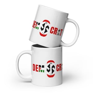 May include: Two white ceramic mugs with a red, black, and green design. The design features a stylized symbol and the text "DEM. S CRAT".