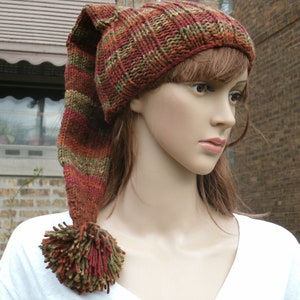 May include: A brown, green, and red striped knit hat with a long, pointed tail and a pom-pom at the end.