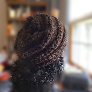 May include: A brown knitted hat with a unique twisted design. The hat is made of a soft, textured yarn and has a slouchy fit.