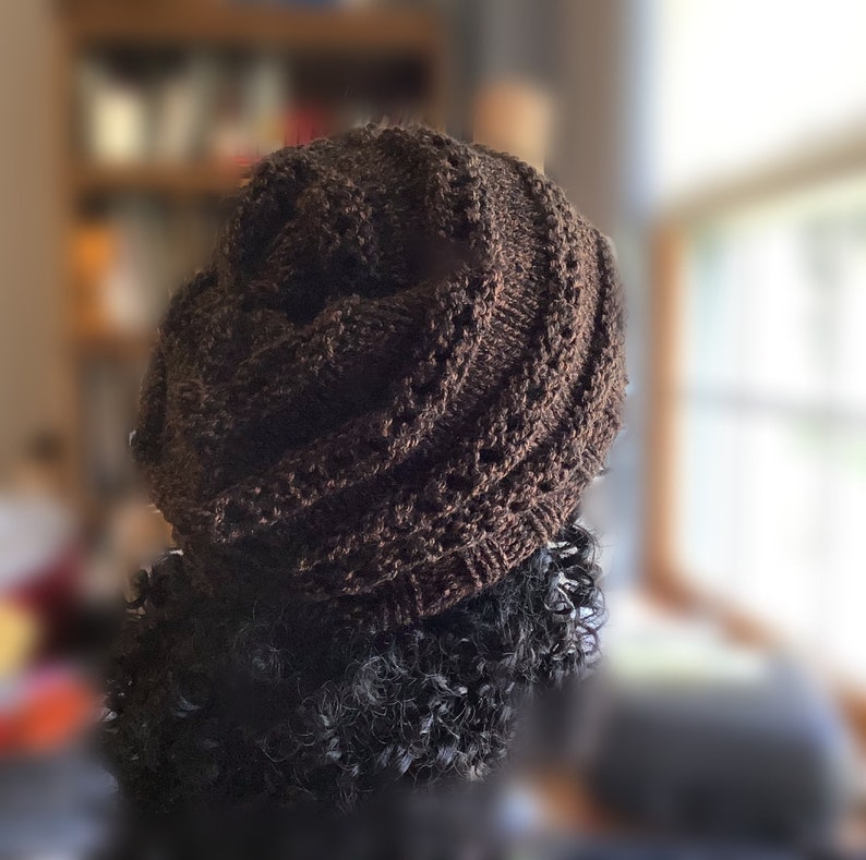 May include: A brown knitted hat with a unique twisted design. The hat is made of a soft, textured yarn and has a slouchy fit.