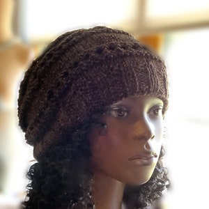 May include: A brown knitted beanie with a textured pattern. The beanie is worn on a mannequin with dark curly hair.