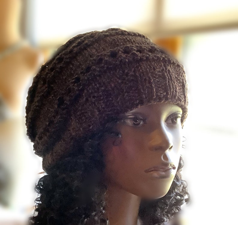 May include: A brown knitted beanie with a textured pattern. The beanie is worn on a mannequin with dark curly hair.