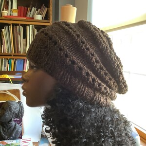May include: A brown knitted beanie with a textured pattern. The beanie is slouchy and has a fold-over brim.