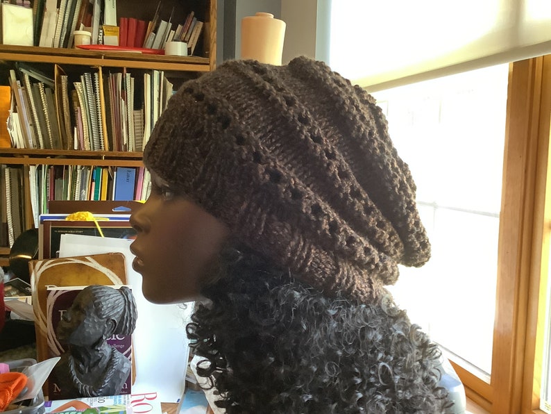 May include: A brown knitted beanie with a textured pattern. The beanie is slouchy and has a fold-over brim.