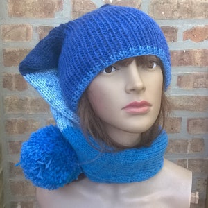 Puede incluir: Un gorro azul de punto con una solapa de oreja larga y puntiaguda y un pomp&oacute;n a juego. El gorro se combina con una bufanda de punto azul.