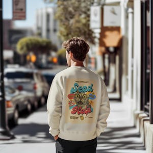 May include: Cream-colored sweatshirt with a graphic on the back featuring a distressed cat illustration and the words "Send Help" in a retro font. The design includes colorful speech bubbles and a hand symbol.