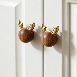 May include: Two decorative cabinet knobs with a reindeer design. Each knob features a round, dark wood base with gold-colored antlers. The knobs are mounted on a white cabinet door, adding a touch of whimsy to the furniture.