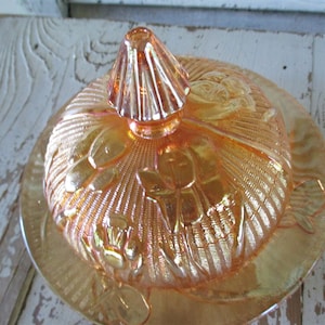 May include: A vintage amber glass butter dish with a floral design. The dish has a domed lid with a fluted knob.