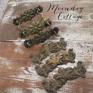 May include: Antique brass drawer pulls and handles. The image shows several vintage drawer pulls and handles in various designs, including floral and ornate scrollwork. The text "Moondog Cottage" is visible in the upper right corner.