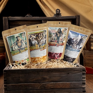 May include: Four bags of snacks with illustrations of mythical creatures and the text "Sasquatch's Elusive Trail Mix", "Buffalo Ranch Chex", "Australian Red Yowie Licorice", and "Chocolate Yeti Almonds".
