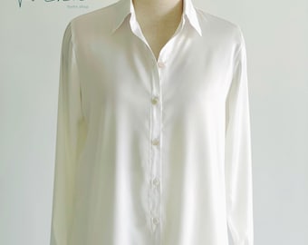 May include: A white long-sleeved button-down shirt with a collared neckline. The shirt is made of a smooth, silky fabric.