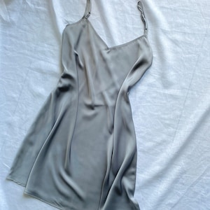 K&ouml;nnte beinhalten: Ein graues Satin-Schlafkleid mit d&uuml;nnen Tr&auml;gern.