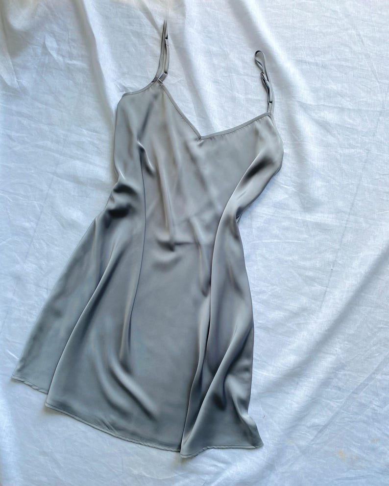 K&ouml;nnte beinhalten: Ein graues Satin-Schlafkleid mit d&uuml;nnen Tr&auml;gern.