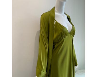 May include: A solid olive green satin pajama set consisting of a sleeveless camisole with thin straps and a matching long-sleeved robe. The fabric has a smooth, reflective finish, and the garments feature a simple, clean-cut design on a mannequin.