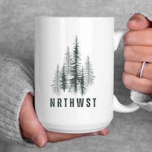 May include: White ceramic mug with a graphic of a forest of pine trees and the text "NRTHWST" in a distressed font.