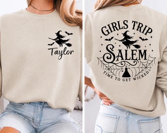 May include: A beige crewneck sweatshirt featuring a black graphic of a witch on a broomstick and the name Taylor on the front left chest. The back displays a large black graphic with the text Girls Trip Salem Time To Get Wicked.