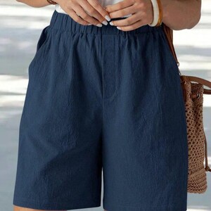 May include: Navy blue shorts with an elastic waistband and pockets. The shorts are made of a textured fabric and have a relaxed fit. The shorts are knee-length and suitable for casual wear.