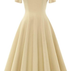 Puede incluir: Un vestido beige claro con escote de coraz&oacute;n y mangas cortas acampanadas. El vestido tiene un corpi&ntilde;o ajustado y una falda fluida.