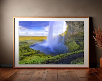 Könnte beinhalten: Ein gerahmtes Foto eines Wasserfalls, der in einen Wasserpool stürzt, umgeben von grünem Gras und einer felsigen Klippe. Der Himmel ist blau mit weißen Wolken.