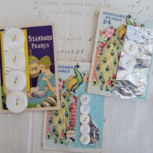 May include: Vintage button cards featuring white pearl buttons. The cards have illustrations of a woman and a peacock. The text on the cards reads "Standard Pearls" and the numbers "36" and "24".