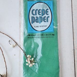 May include: A package of green crepe paper, flame resistant, 125 square feet, 20 inches wide by 2 yards long. The package is labeled "Dennison crepe paper, flame resistant".