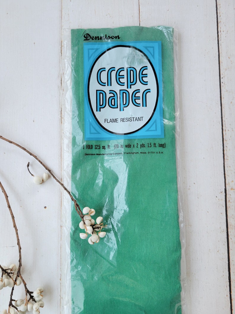 May include: A package of green crepe paper, flame resistant, 125 square feet, 20 inches wide by 2 yards long. The package is labeled "Dennison crepe paper, flame resistant".
