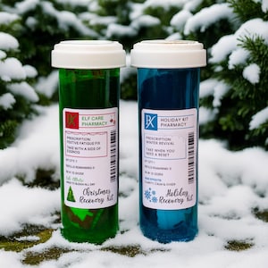 May include: Two novelty pharmacy bottles, one green and one blue, with white lids. The green bottle reads "Elf Care Pharmacy" and "Christmas Recovery Kit." The blue bottle reads "Holiday Kit Pharmacy" and "Holiday Recovery Kit."