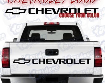 May include: Black Chevrolet logo and text decals on a white truck bed. The decals include the Chevrolet logo and the word "CHEVROLET" in a bold font. The text "CHOOSE YOUR COLOR" is also visible.