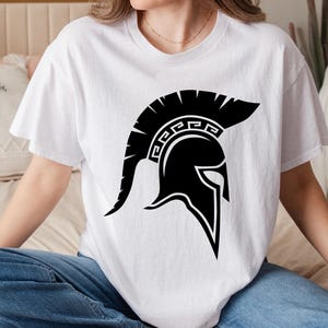 May include: A white t-shirt with a black graphic of a Spartan helmet. The helmet has a design of a Greek key pattern.