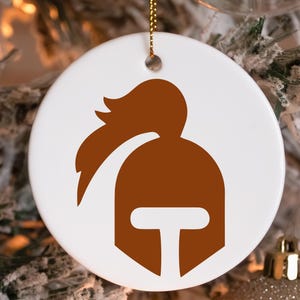 May include: A white ceramic ornament with a brown silhouette of a knight's helmet with a plume on top.