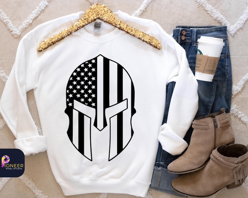May include: White sweatshirt with a black and white graphic of an American flag inside a Spartan helmet.