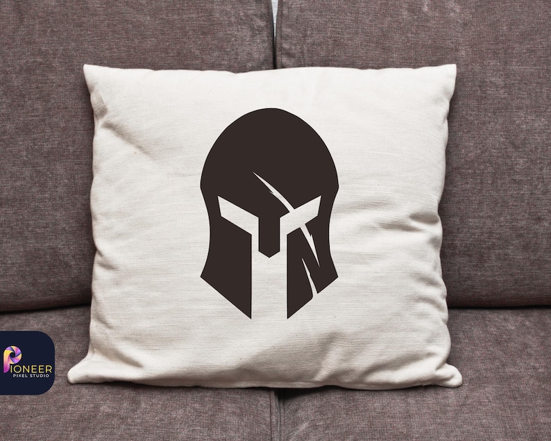 May include: A white pillow with a black silhouette of a spartan helmet in the center.