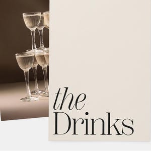 Op de afbeelding: Een stapel heldere glazen cocktailglazen tegen een lichtbruine achtergrond. De tekst "the. Drinks" is in zwart op een witte achtergrond gedrukt.