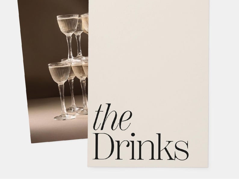 Op de afbeelding: Een stapel heldere glazen cocktailglazen tegen een lichtbruine achtergrond. De tekst "the. Drinks" is in zwart op een witte achtergrond gedrukt.